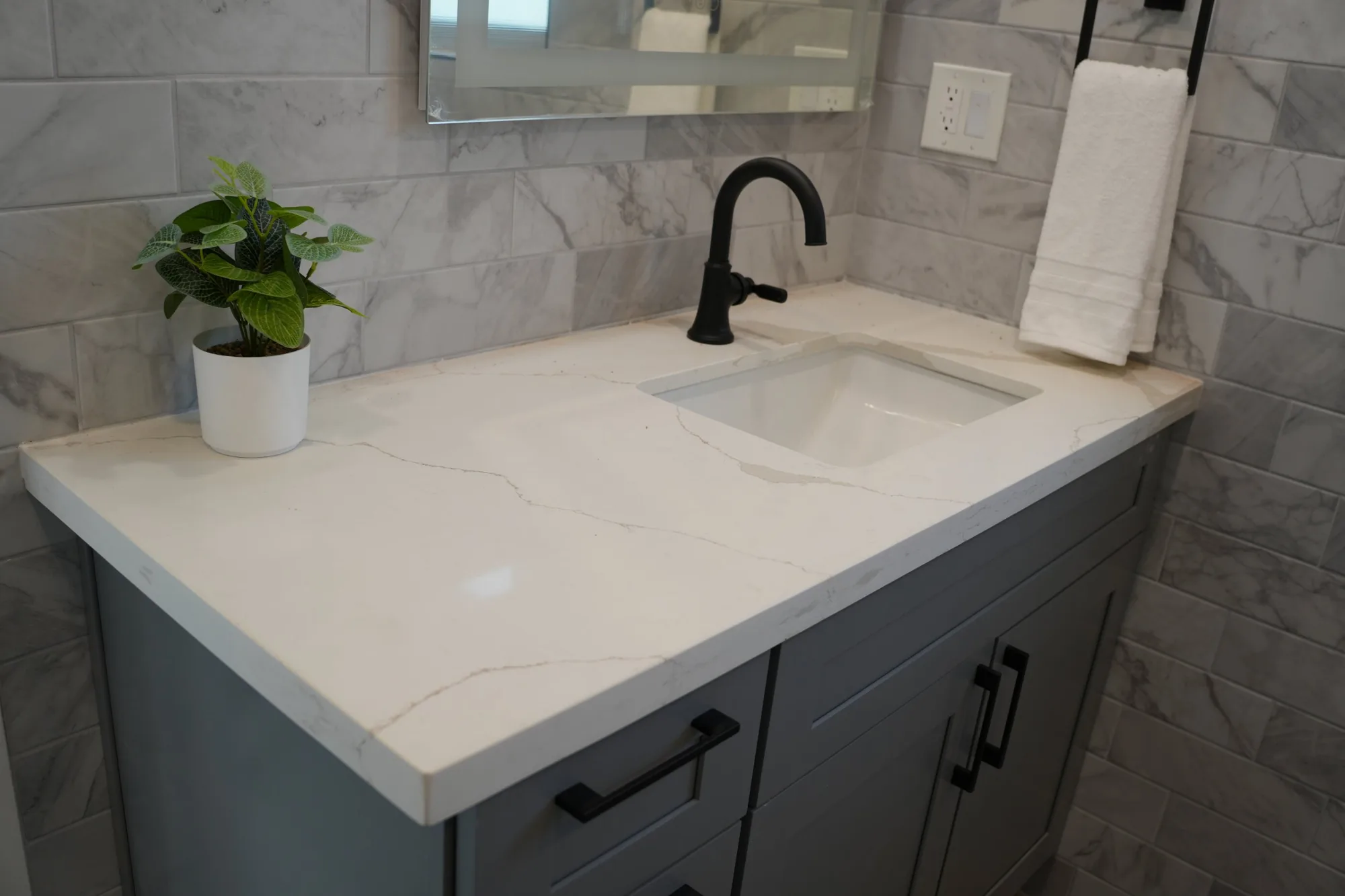 Gray vanity with a white veined countertop and black faucet
