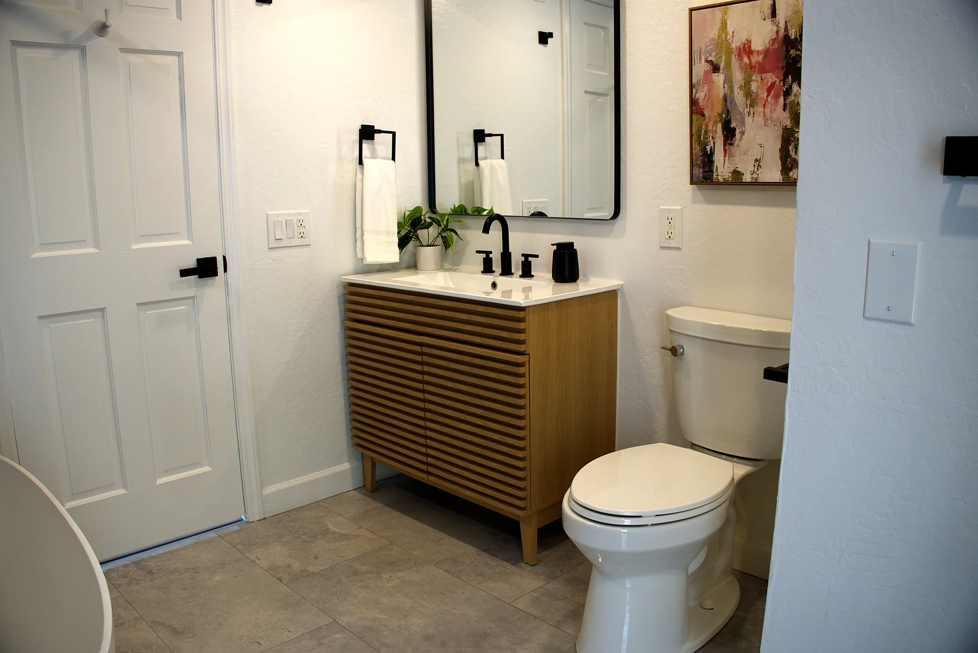 Slatted wood vanity with a black framed mirror