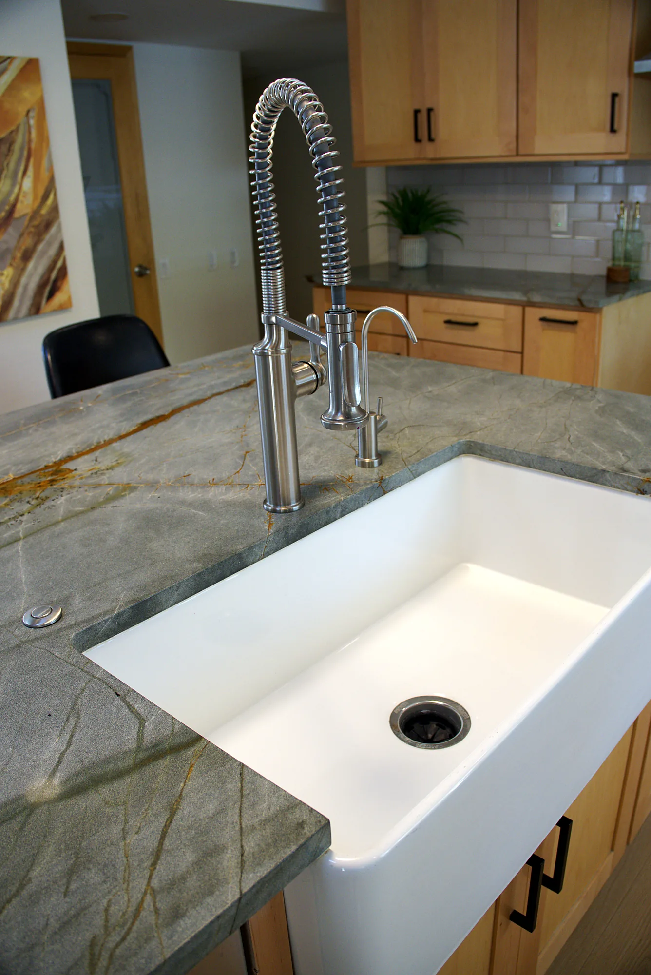 White farmhouse sink with a spring faucet in a stone countertop