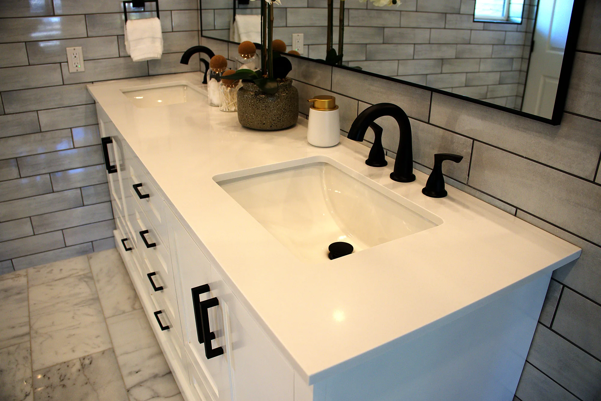 Close up of a white vanity top with black faucets and hardware